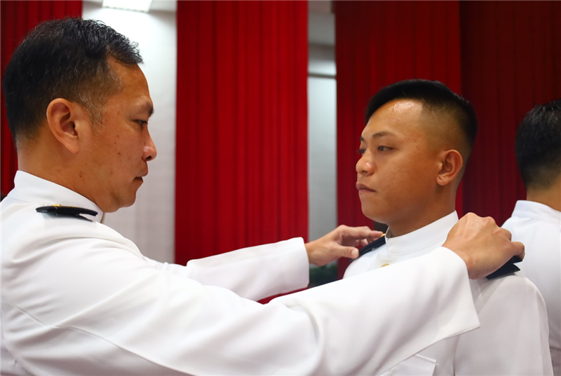 Command Sergeant Major Huang pins rank insignia on a graduating trainee
